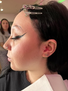 Precise winged liner and multiple lobe piercings on a Skin Lab client.