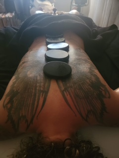 Hot stone massage placement along a tattooed back.