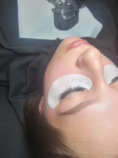 Lash extensions in progress with under-eye pads placed.