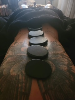 Warm basalt stones aligned along a tattooed spine.